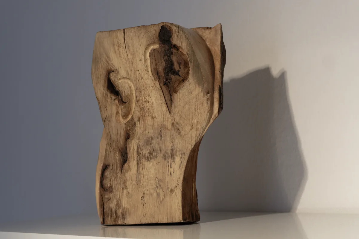 Holzskulptur mit zwei einander zugewandten Gesichtsprofilen auf einem Praxis-Regal