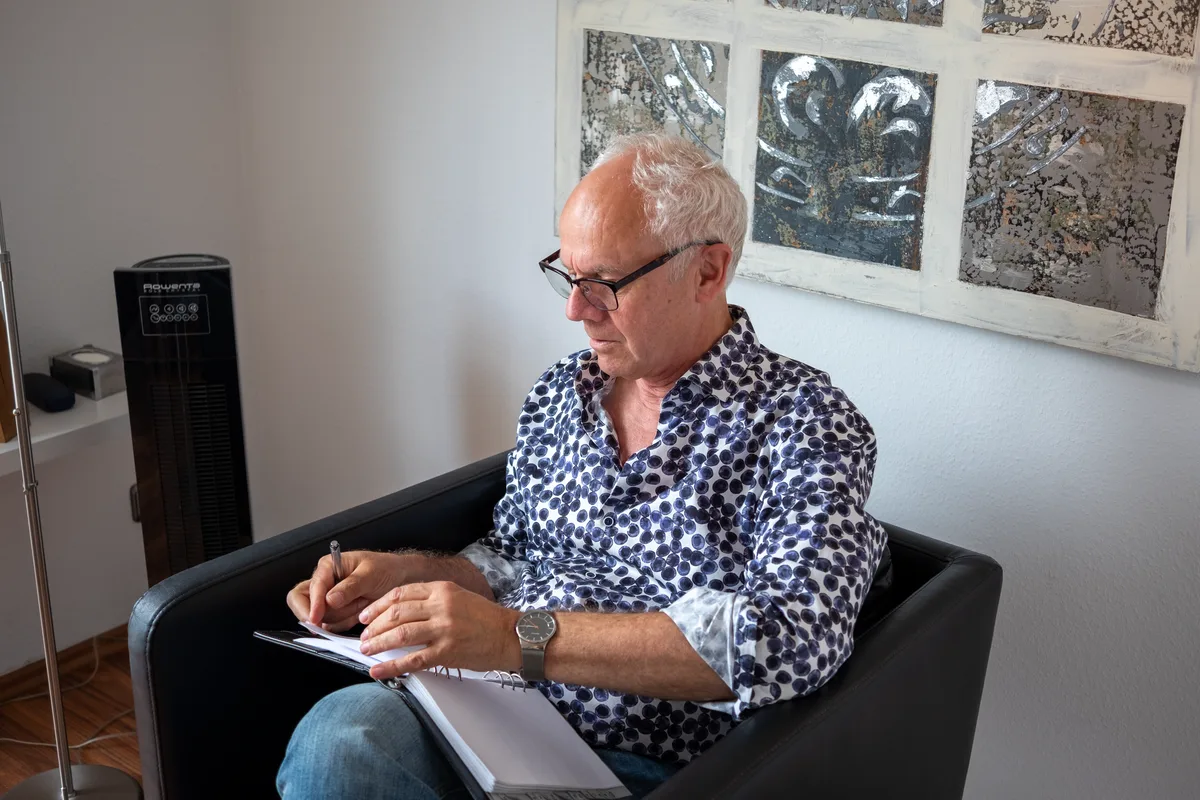 Volker van den Boom im beratenden Gespräch mit Blick auf seine Notizen – Praxis in Aachen Volker van den Boom im beratenden Gespräch mit Blick auf seine Notizen – Praxis in Aachen